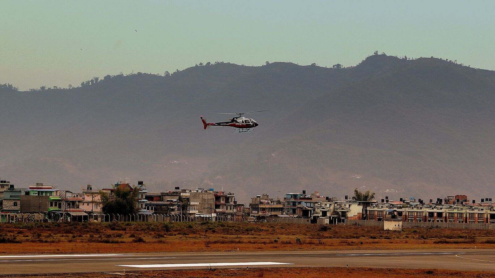 A twin-engined charter helicopter settling onto the apron at Pokhara.