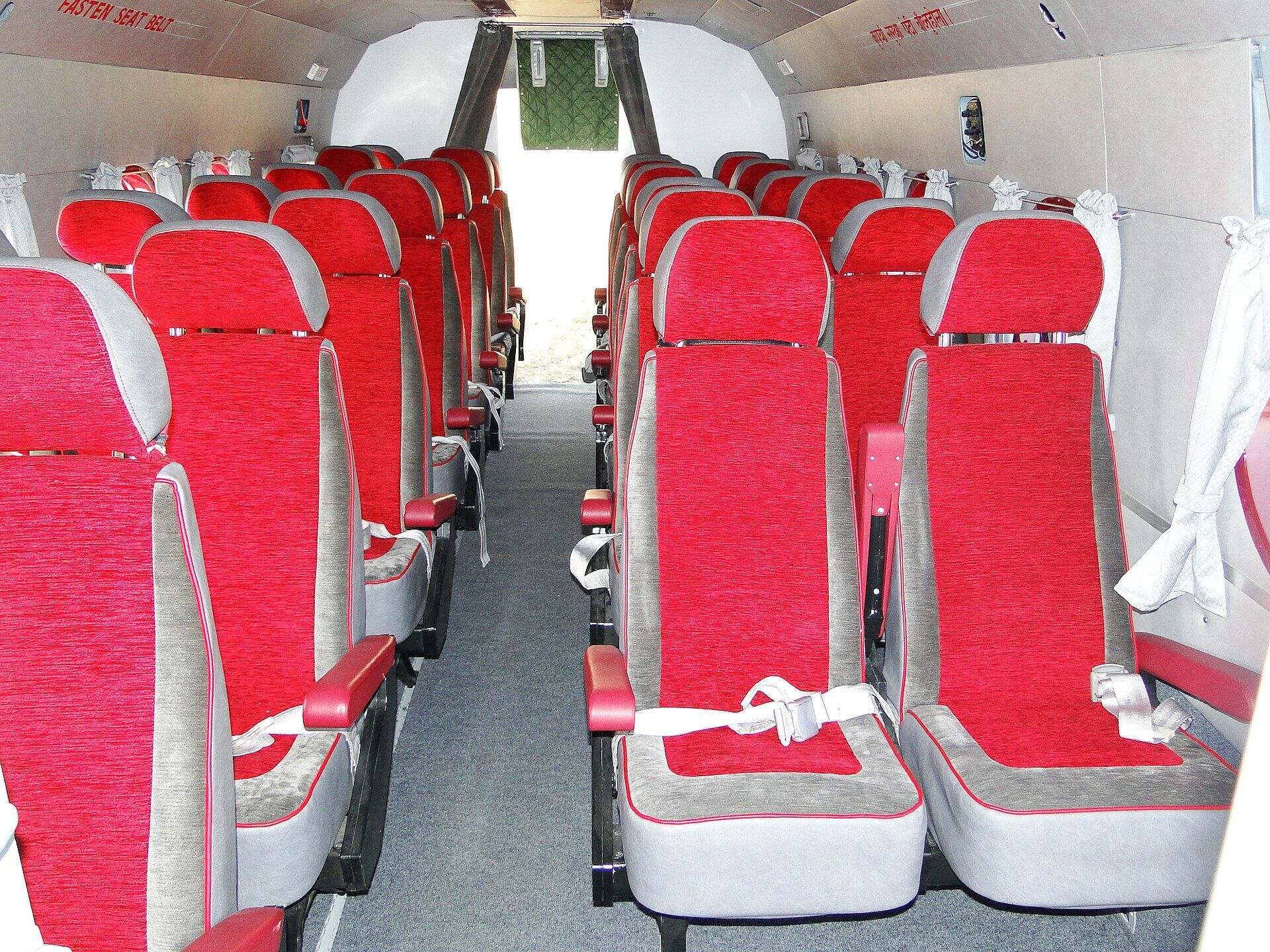 The passenger cabin of a Nepali charter helicopter, two rows of seats belted and empty, the door open at the far end.