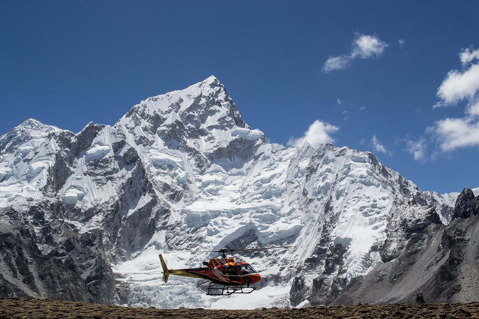 A helicopter lifting away from Everest Base Camp, Nuptse in the foreground.