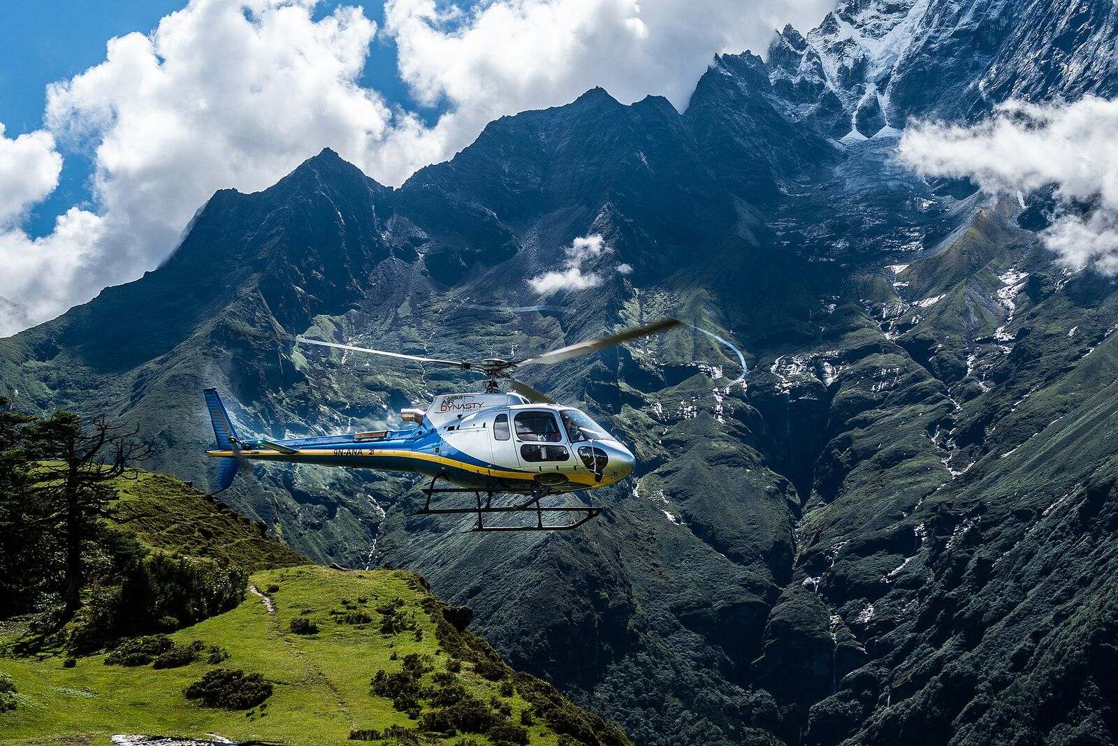 An Airbus H125 in the cruise above the Solukhumbu, Himalayan faces rising behind it.