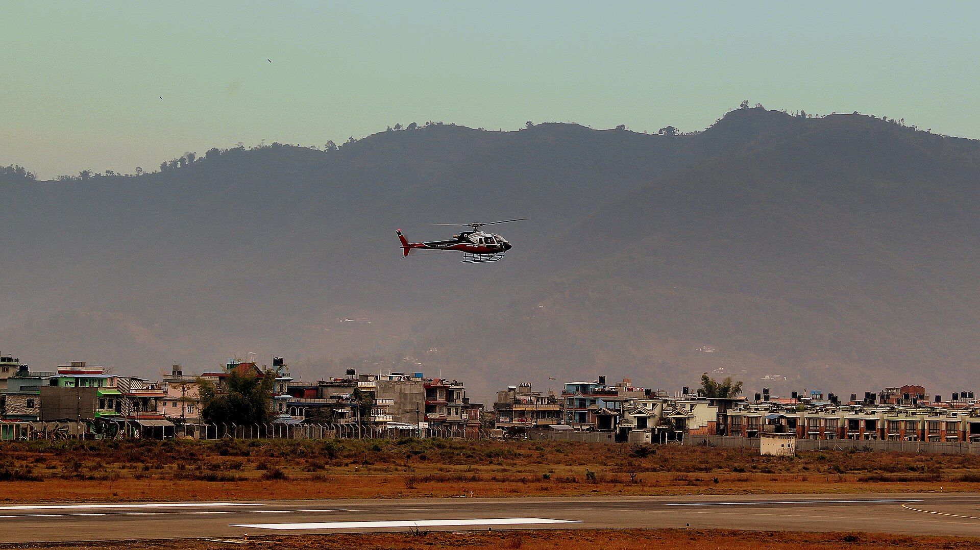 A twin-engined charter helicopter settling onto the apron at Pokhara.